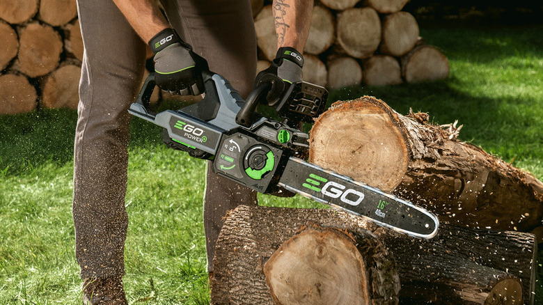 person cutting a log with an Ego chainsaw