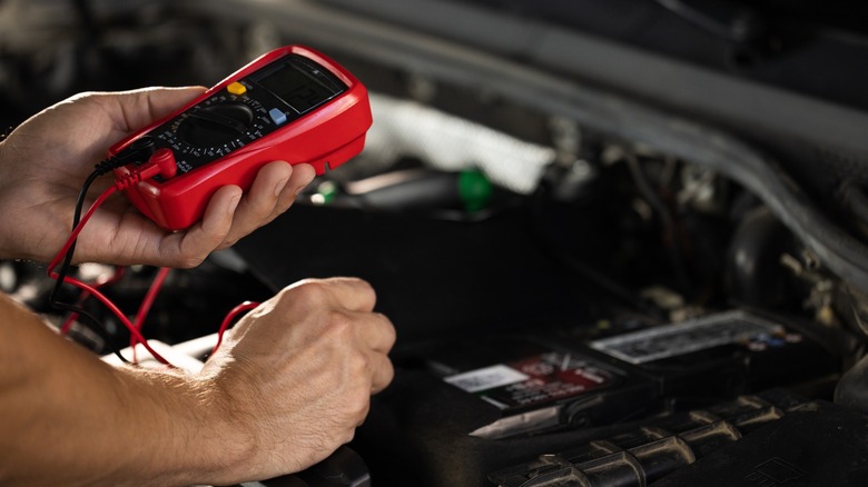 Handheld multimeter and battery tester used to test car battery.