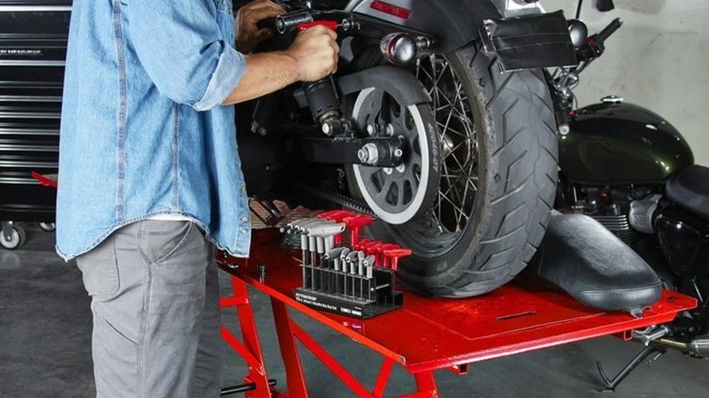 Person maintaining motorcycle with lift