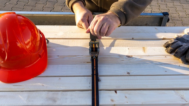 Man using a tie-down on wood planks