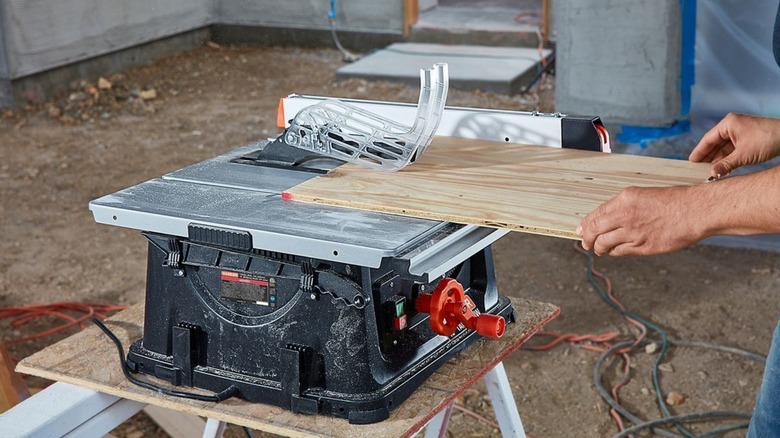 hands pushing wood on Warrior table saw