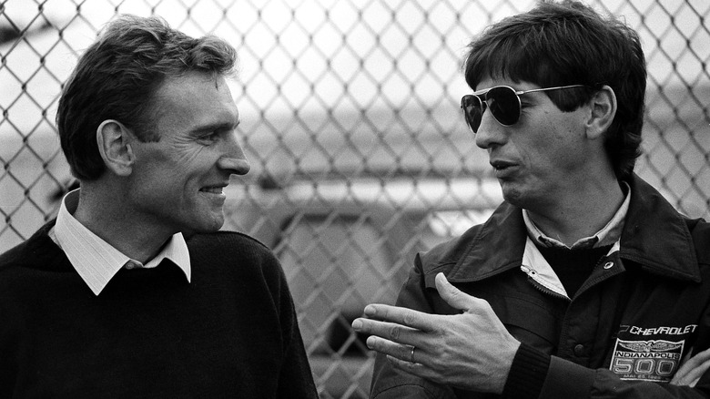 Paul Morgan (left) speaks to Mario Illen (right) in front of a tall fence.