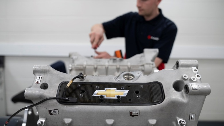 An Ilmor engine with a Chevrolet logo on the block with a mechanic working behind it