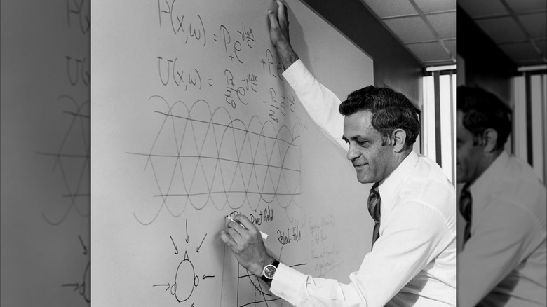 Dr. Amar Bose writing on a whiteboard with a marker.