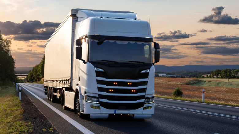 Truck driving on road at sunset