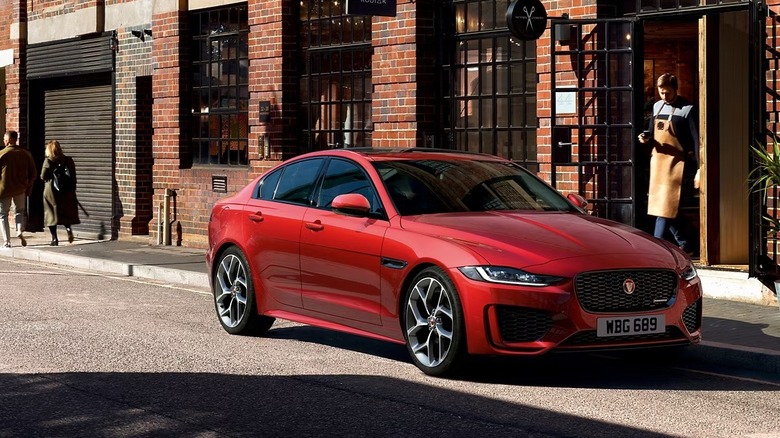 Red Jaguar XE parked in front of an establishment with people walking on the sidewalk