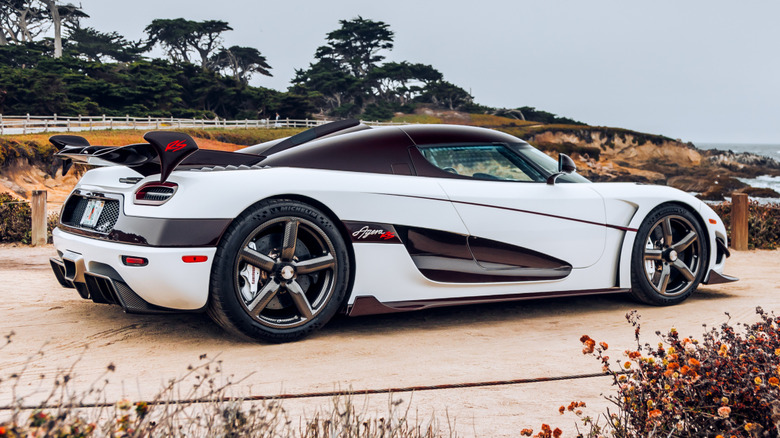 A white Koenigsegg car parked on a beach.