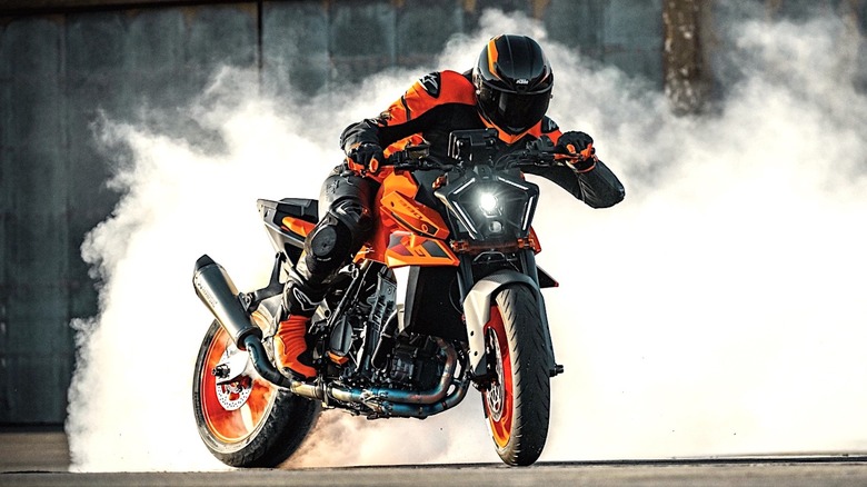 Person revving KTM motorcycle to smoke the tires on the street