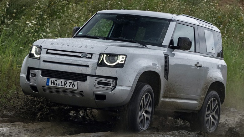 A Land Rover Defender driving on a muddy trail