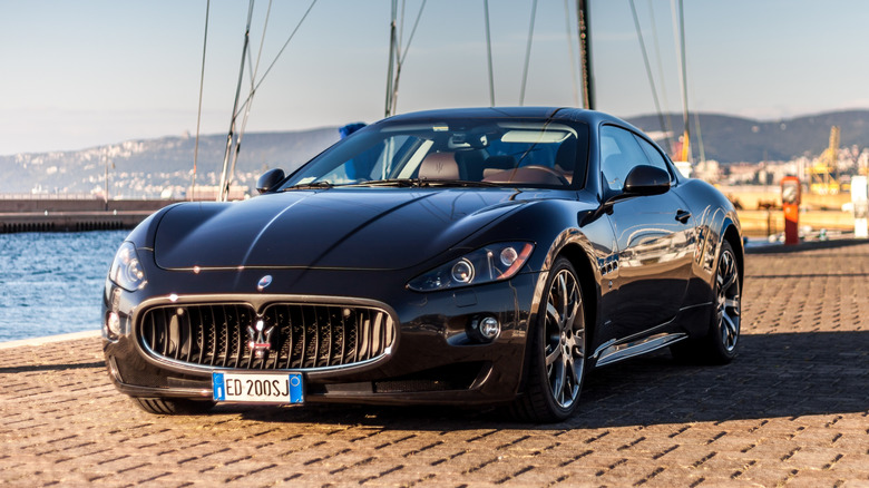 A black Maserati GranTurismo S parked on cobblestone.