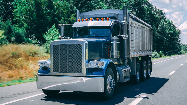 A diesel dump truck driving down a road.