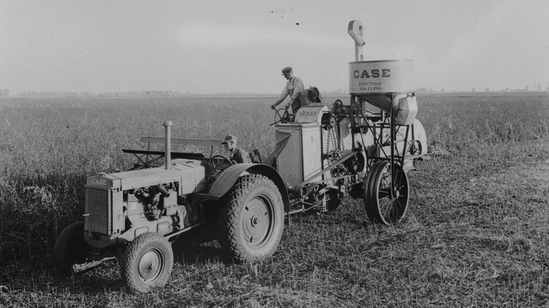 A 1930s farmer working on a tractor in a wheat field.