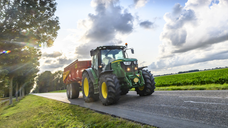 Green John Deere tractor driving down road