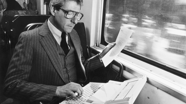 A publicity photograph shows a businessman using a Hewlett-Packard laptop while traveling on a train.