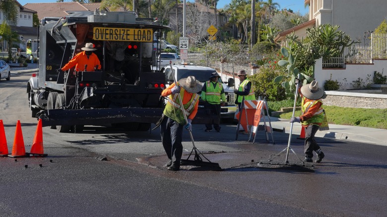 Workers helping seal coat road