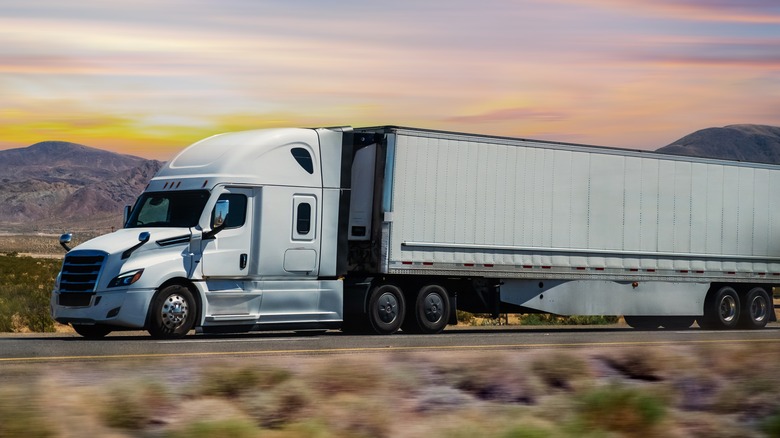 A white semi-truck driving through a desert