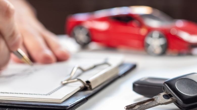 Close up shot of documents, a car key, and a toy car.