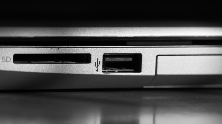 A black USB port next to SD card reader slot on a silver laptop