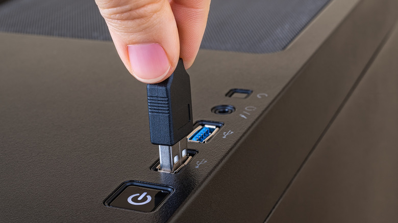 PC tower with blue USB port and person plugging USB calbe into port