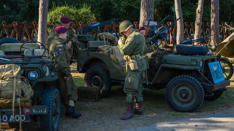 People in 1940s vintage army uniforms standing next to Willys MB Jeep