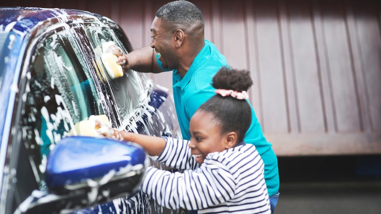 Adult and child washing a car togeth