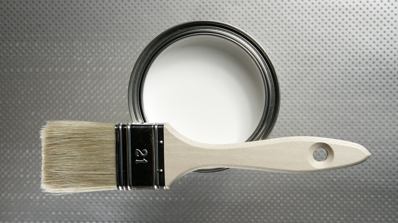 Can of white paint with brush