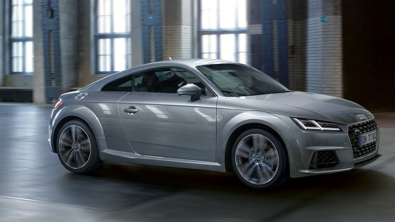 A motion-blurred gray Audi TT driving inside a building