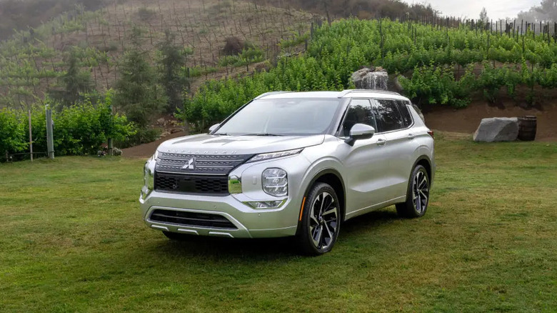 Silver Mitsubishi Outlander parked in field near grove of trees