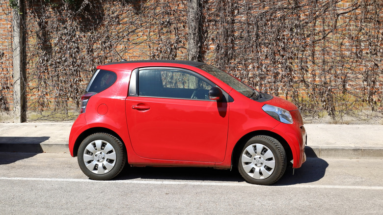 Side view of red Scion iQ with brick wall in background