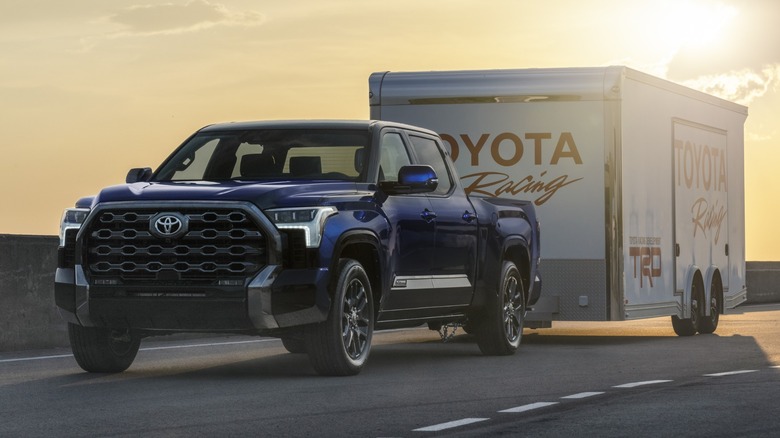 A 2022 Toyota Tundra towing a Toyota Racing trailer backlit by the sun