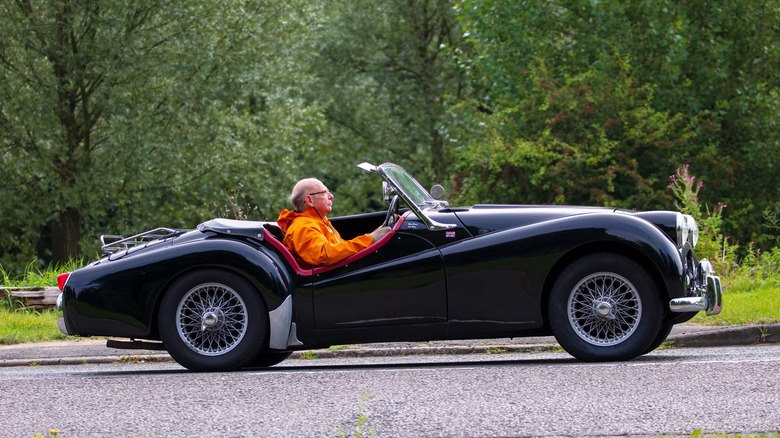 Elderly man driving black 1955 Triumph TR2