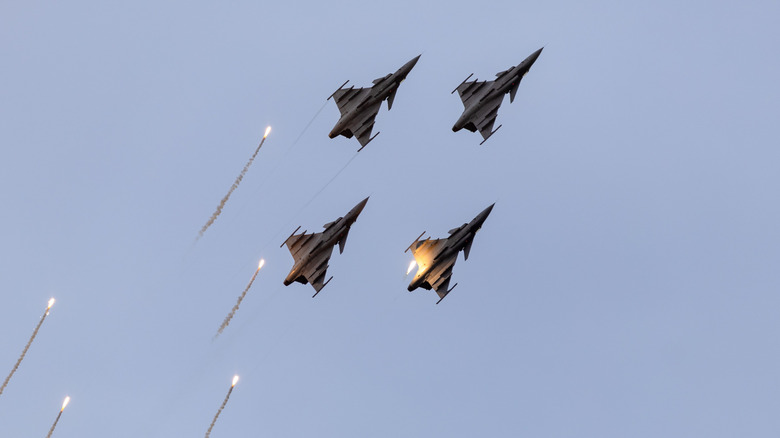 Four fighter jets dropping flares.