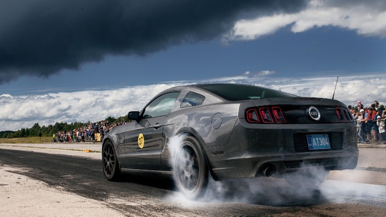 rear view of a Ford Mustang burning out tires on a track