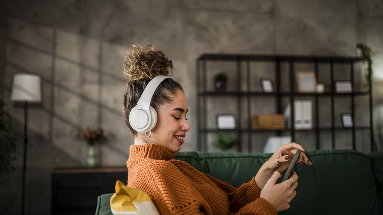 A woman sits while listening to music from her phone using her headphones