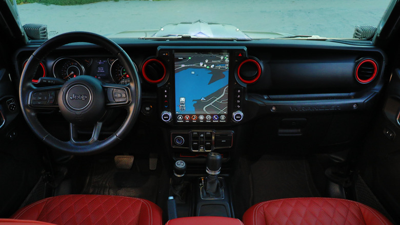 The inside of a Jeep Wrangler, showing manual gear shift and navigation screen