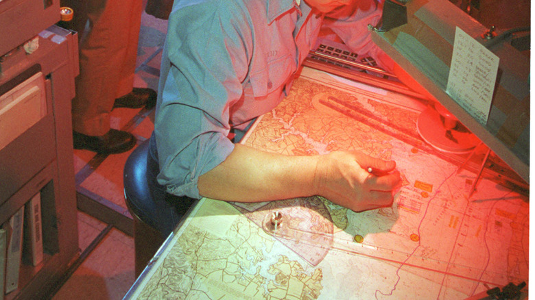 Submariner looking at charts under red light