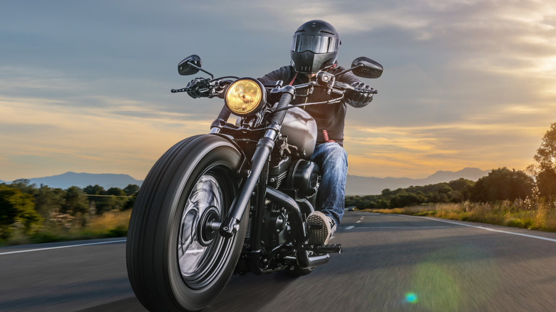 A motorcycle rider on their bike wearing a leather jacket.