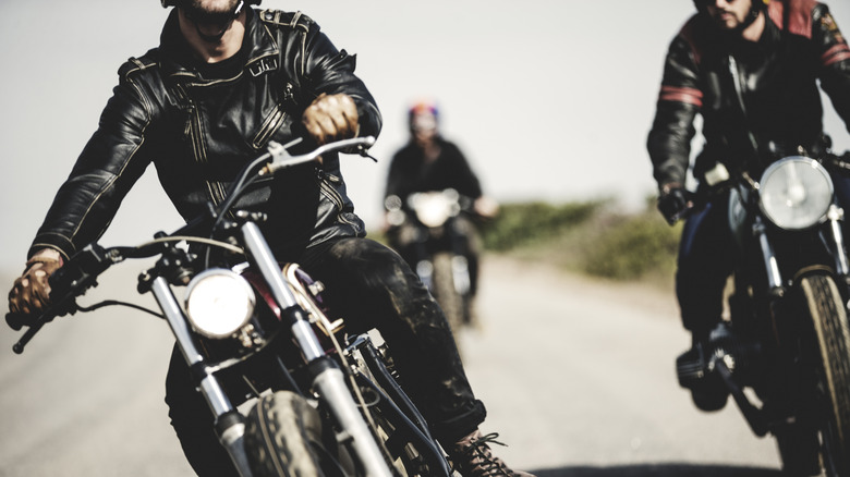 Three motorcycle riders wearing leather jackets.