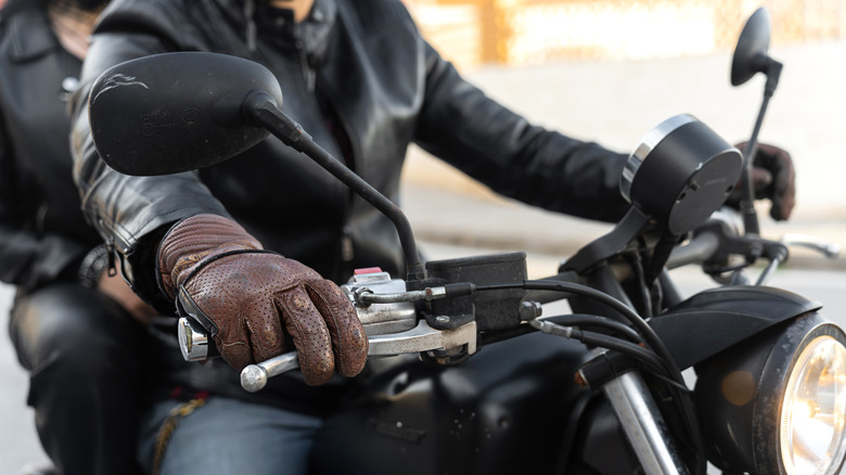 A biker wearing a leather jacket and leather gloves.