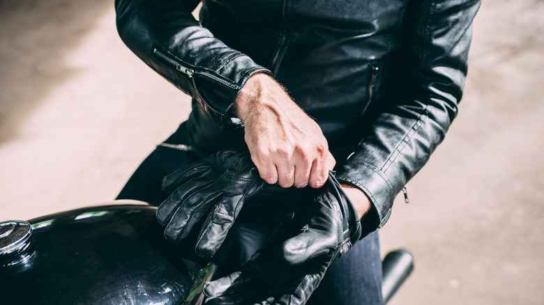 A motorcyclist putting on a leather glove.