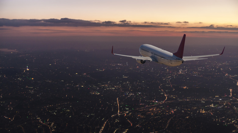 An airplane flying over a city at dusk