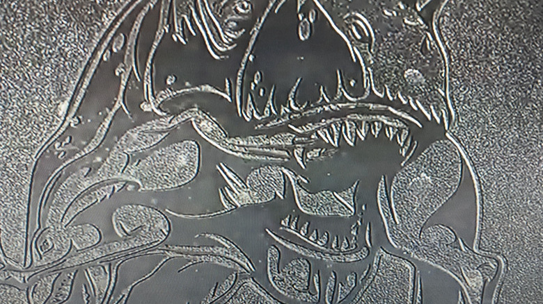 Embossed image of the Tyrannosaurus rex devouring a Velociraptor on a Ram 1500 TRX airbox cover,