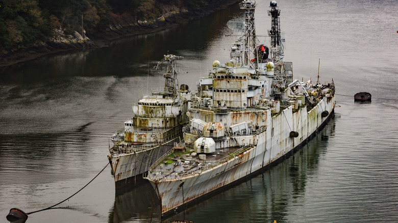 Two naval vessels docked and rusting