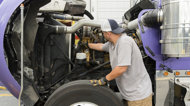 Man Examines Truck Engine