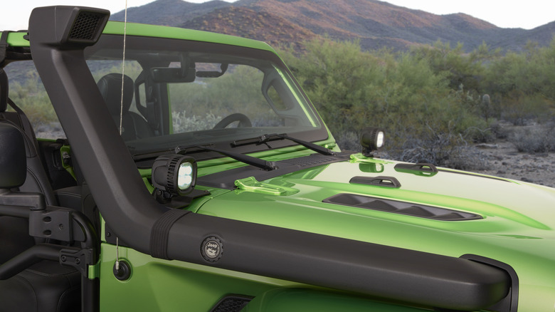 A green Jeep with a snorkel mounted on its right side