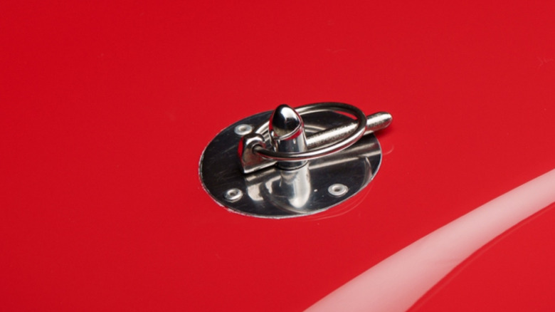 A hood pin on a red first-generation Mustang.