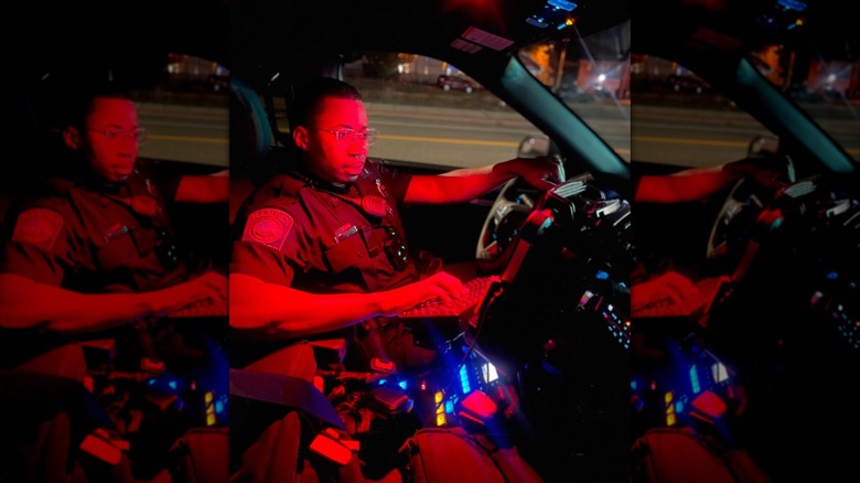 Officer Joyner of Hamden Police Department sitting in his patrol car lit by red interior lights