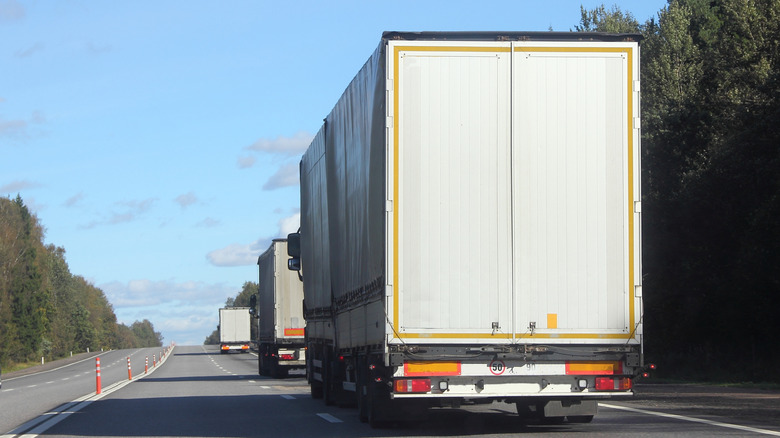 A series of three trucks running in the middle of the road