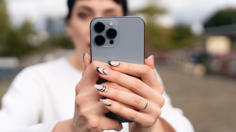 A woman taking photo with iPhone in outdoor setting