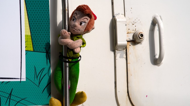 A Peter Pan plushie tied to a garbage truck.